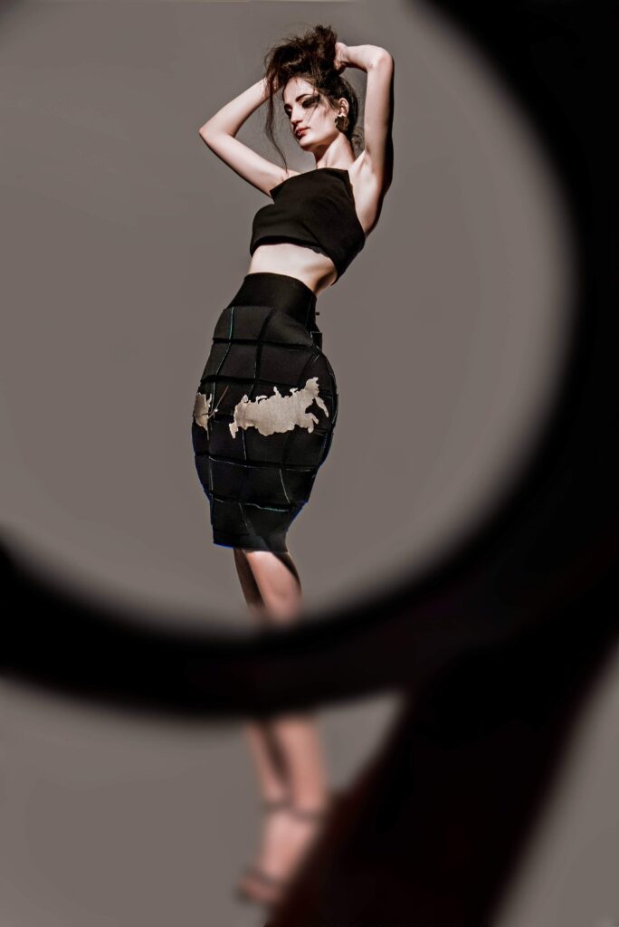 Haljina i suknja pod nazivom “Minsko polje”, dizajn Ljiljane Majkić, nagrađeni rad u kategoriji Modni dizajn na Collegium Artisticum 2021. Fotografije prikazuju model u crnoj haljini i suknji inspirisanoj konceptom minsko polje.