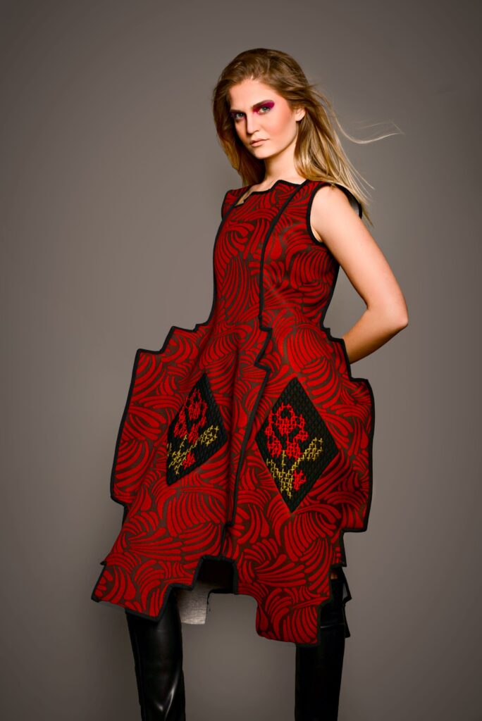 Model u crvenoj haljini s crnim dezenom iz kolekcije “Toplina šare” Ljiljane Majkić, nagrađena na Collegium Artisticum 2023 u kategoriji modnog dizajna