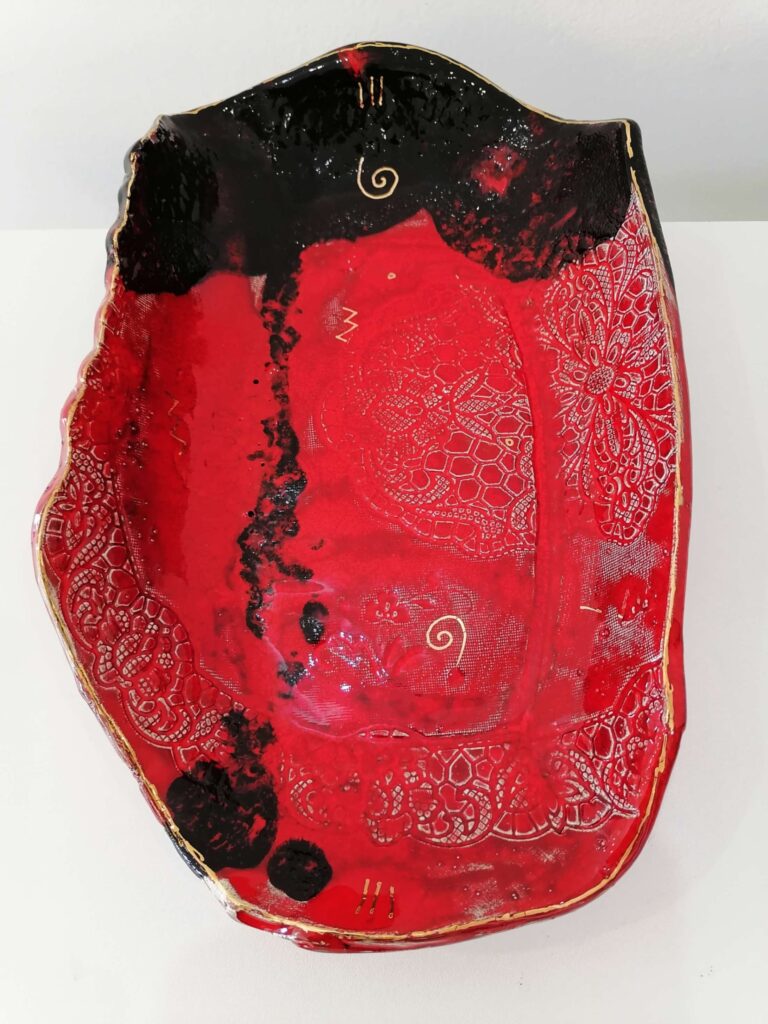 Keramička zdjela “Itinerarium 2” autorice Halide Emrić, nagrađeni rad na Collegium Artisticum 2021 u kategoriji Unikatno oblikovanje. Zdjela je ručno oblikovana u crvenoj i crnoj boji, s dekorativnim motivima i zlatnim detaljima.